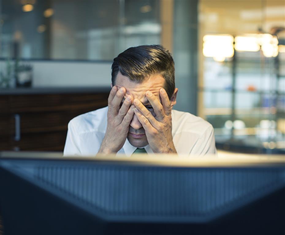 A businessman peaking at a computer screen